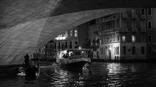 Gondola a vaporetto podplouvající pod obloukem Ponte di Rialto